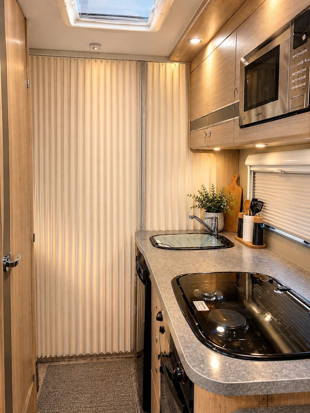 The galley kitchen with microwave, oven and rooflight, and the concertina door to the washroom
