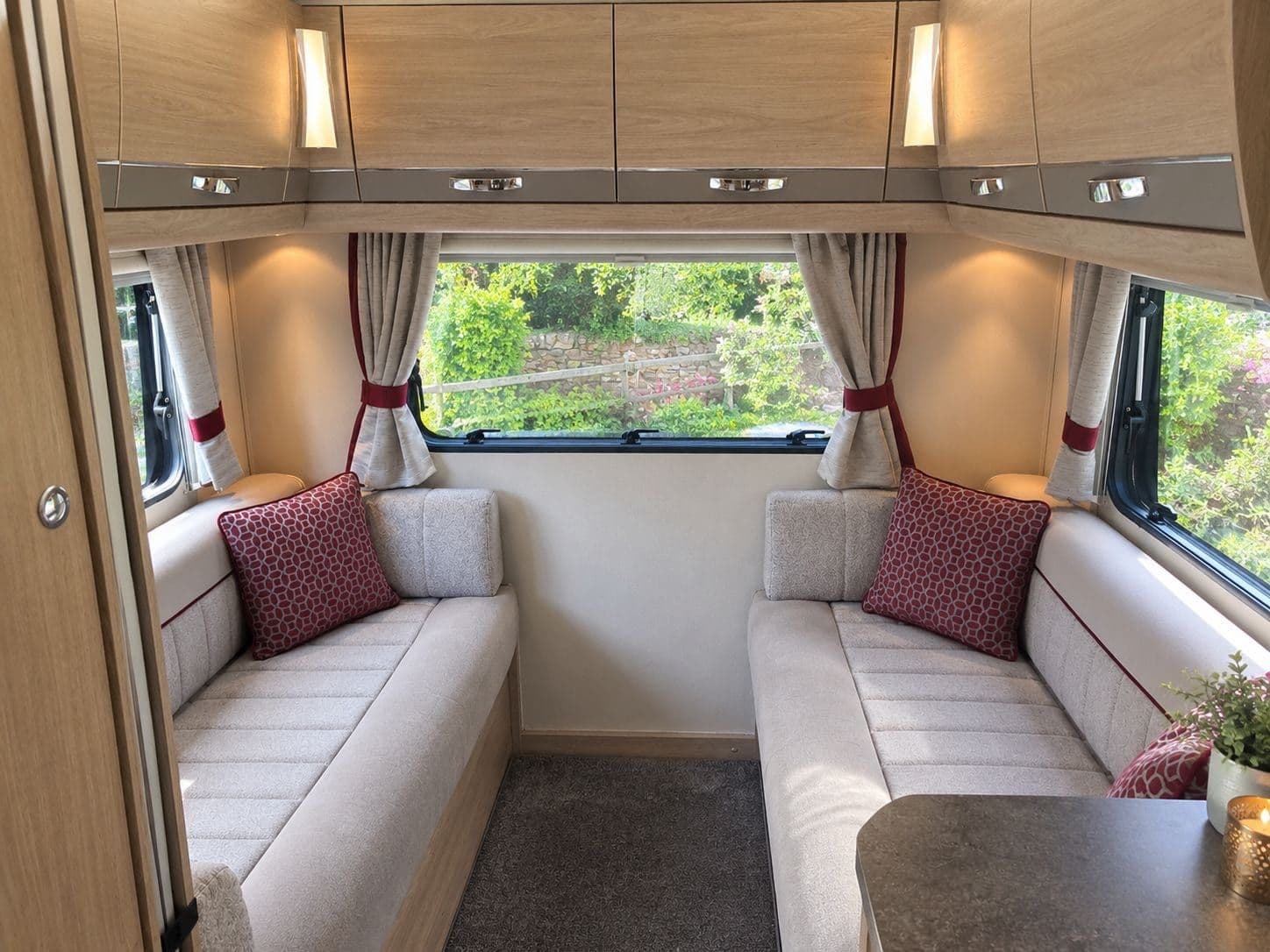 The rear lounge in daylight, two facing sofas with scatter cushions under a wide window